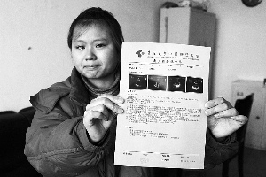 女孩眼含淚水向記者出示自己母親的診斷報(bào)告，希望好心人可以幫幫她的母親。　　攝影 李自強(qiáng)
