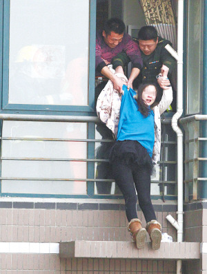 年輕女子在高樓窗外一小平臺(tái)坐了1個(gè)多小時(shí)后，被消防官兵拉進(jìn)屋內(nèi)。