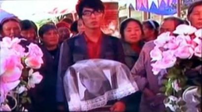 何濱捧著愛人遺像，送上深情一吻。（視頻截圖）